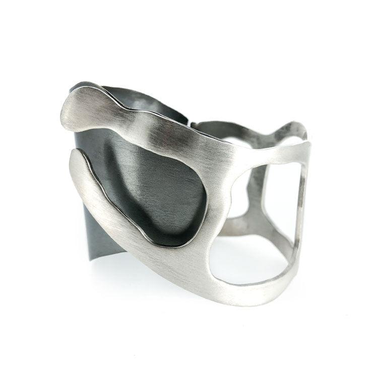 Þetta einstaka handsmíðaða silfurarmband er hluti af Lava Flow skartgripalínunni, innblásinni af glóandi hraunflæði Íslands. Hönnun og smíði eftir Bolla Ófeigsson, þetta glæsilega listaverk er einstakt og aðeins þetta eintak er til - ofeigur.is